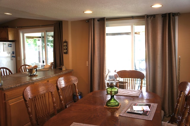 dining area with a textured ceiling and vaulted ceiling