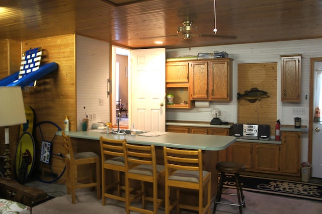 kitchen with a kitchen bar, kitchen peninsula, wooden walls, and wooden ceiling