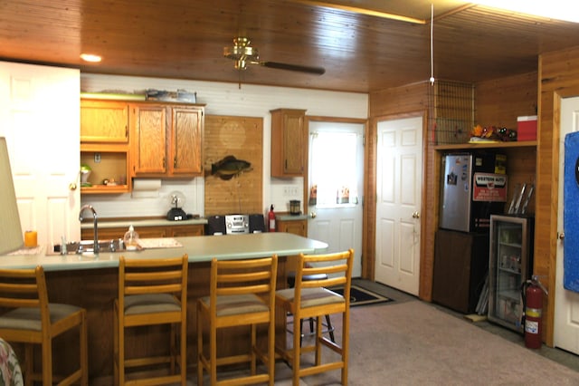 kitchen featuring kitchen peninsula, wood ceiling, ceiling fan, sink, and a breakfast bar area