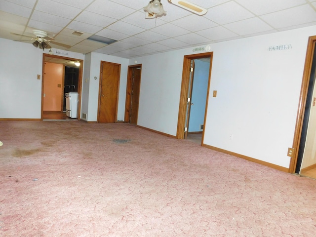 unfurnished room featuring ceiling fan, carpet flooring, washer / dryer, and a drop ceiling