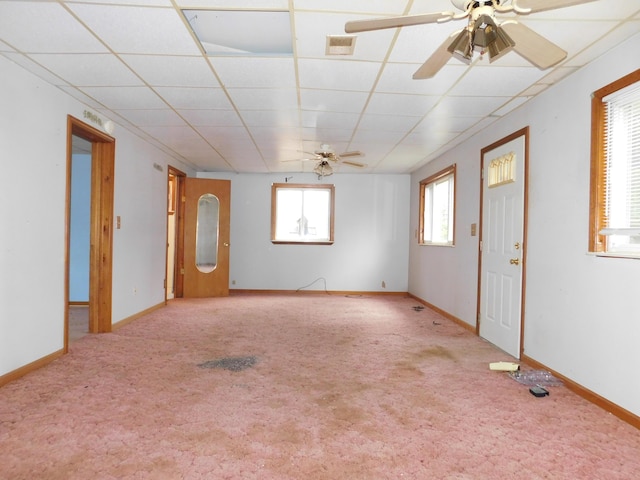 carpeted empty room with ceiling fan and a drop ceiling