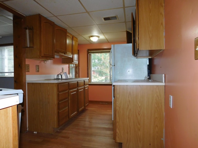 kitchen with a drop ceiling, sink, refrigerator, and light wood-type flooring