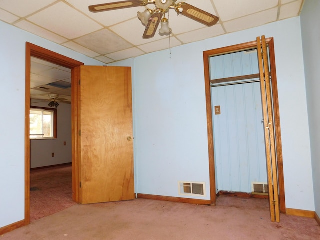 unfurnished bedroom featuring a paneled ceiling, light colored carpet, a closet, and ceiling fan