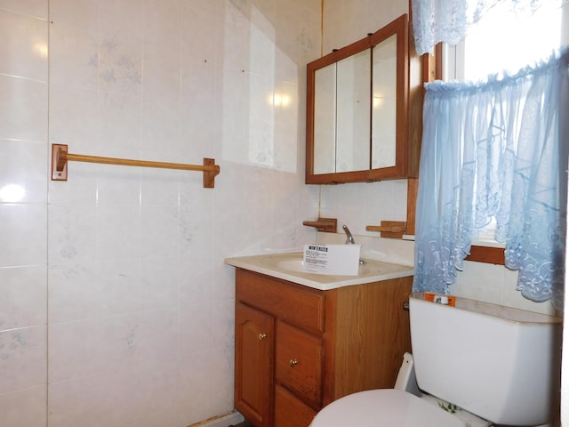 bathroom featuring vanity, tile walls, and toilet