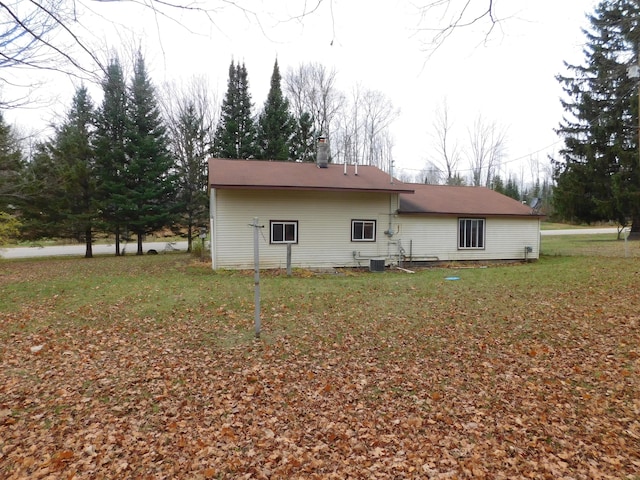 rear view of house with central AC unit and a lawn