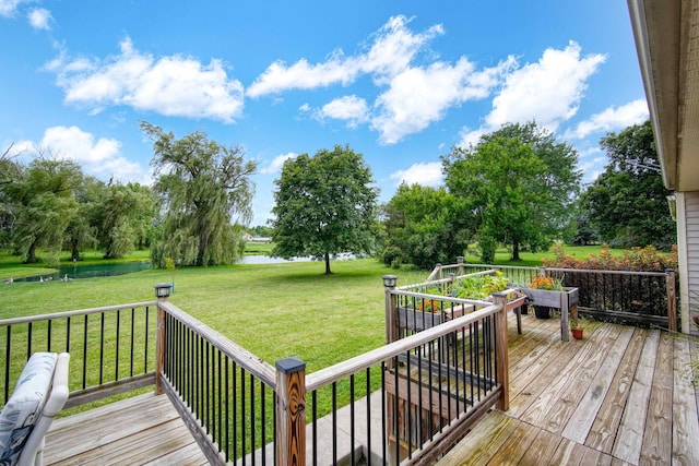 wooden terrace featuring a water view and a lawn