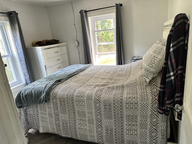 bedroom featuring multiple windows and wood walls