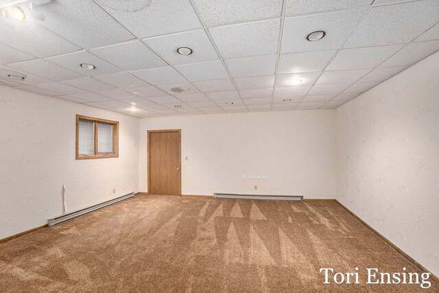 empty room featuring a baseboard heating unit and carpet