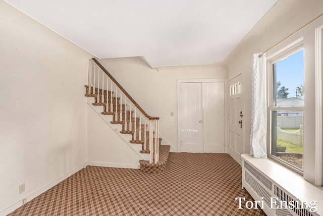 foyer entrance with radiator and carpet flooring