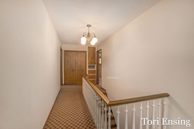 corridor with a chandelier and a textured ceiling