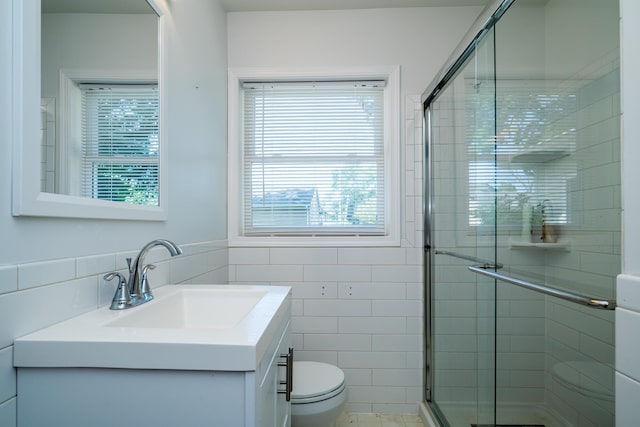 bathroom featuring vanity, a shower with door, tile walls, and toilet