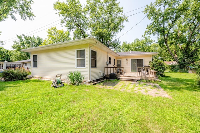 back of house with cooling unit, a deck, and a lawn