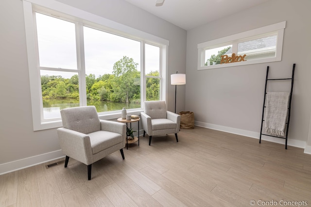 living area featuring a water view and light hardwood / wood-style flooring