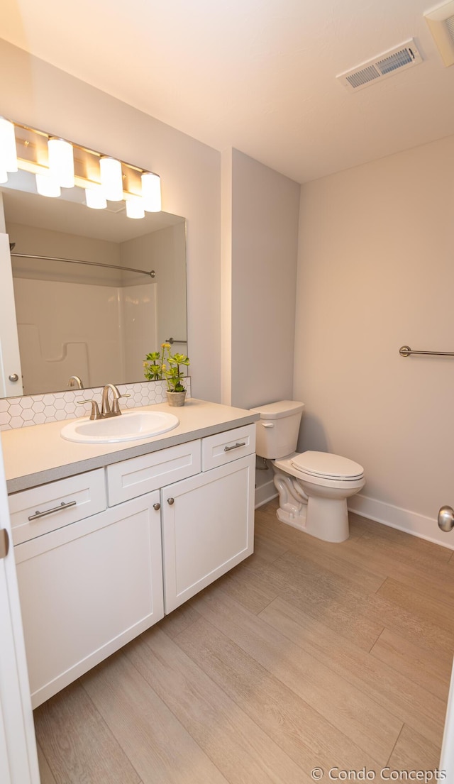 bathroom featuring hardwood / wood-style flooring, vanity, toilet, and a shower