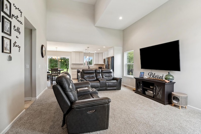 living room featuring a high ceiling, sink, light carpet, and an inviting chandelier