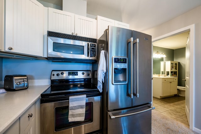 kitchen with appliances with stainless steel finishes, light tile patterned floors, and white cabinets