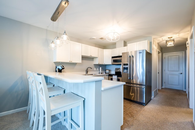 kitchen with sink, appliances with stainless steel finishes, white cabinets, decorative light fixtures, and kitchen peninsula