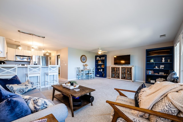 living room with ceiling fan, light colored carpet, and built in shelves