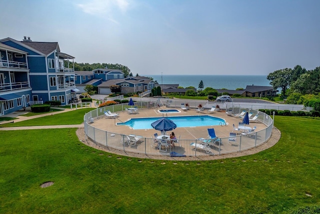 view of swimming pool with a community hot tub, a water view, and a lawn