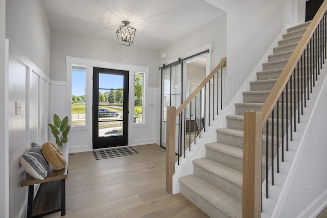 entrance foyer with light hardwood / wood-style flooring, a barn door, and a chandelier