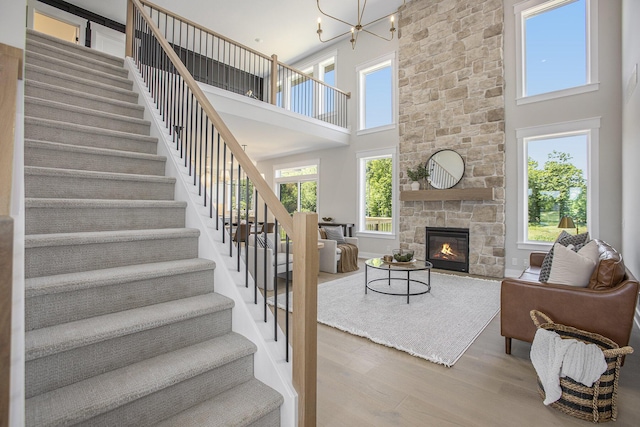 living room featuring hardwood / wood-style flooring, a towering ceiling, a fireplace, and a chandelier