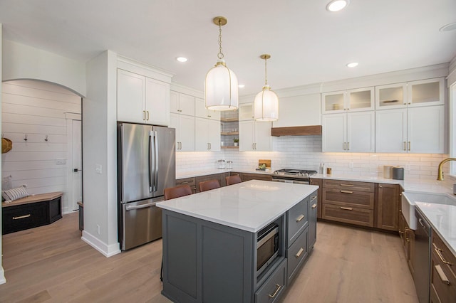 kitchen featuring white cabinets, custom exhaust hood, a center island, light stone counters, and stainless steel appliances