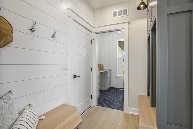 mudroom featuring wooden walls and light hardwood / wood-style floors