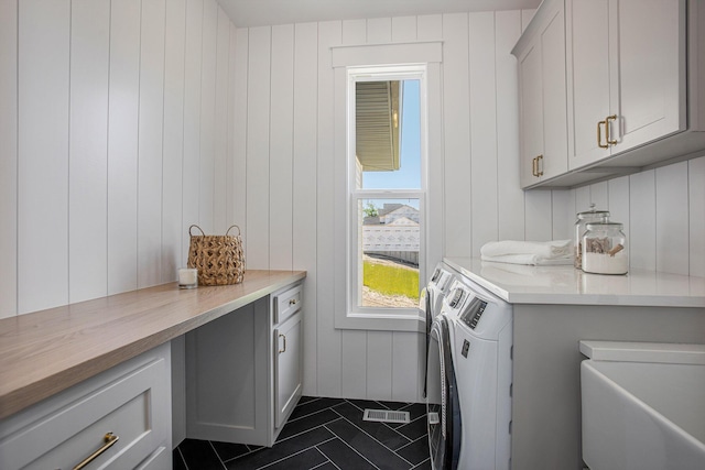 laundry room with cabinets, washer and clothes dryer, and dark tile patterned floors