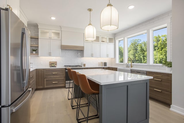 kitchen featuring premium range hood, a center island, stainless steel appliances, light hardwood / wood-style floors, and white cabinets