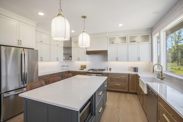 kitchen featuring custom exhaust hood, white cabinetry, appliances with stainless steel finishes, a kitchen island, and light stone countertops