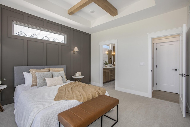 carpeted bedroom featuring beam ceiling, ceiling fan, and ensuite bath