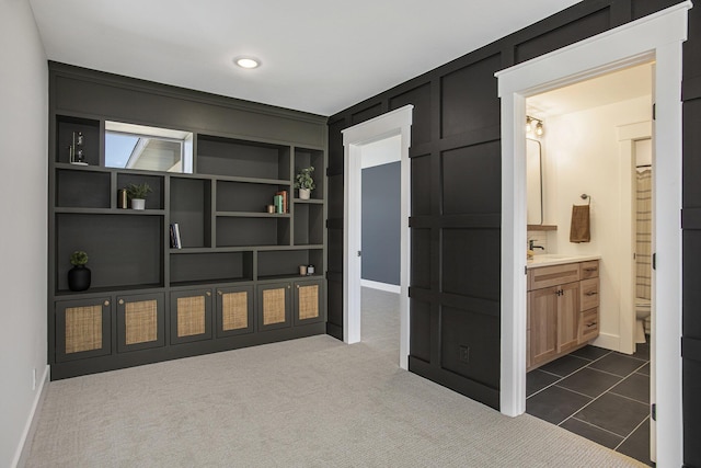 corridor with sink, dark carpet, and built in features