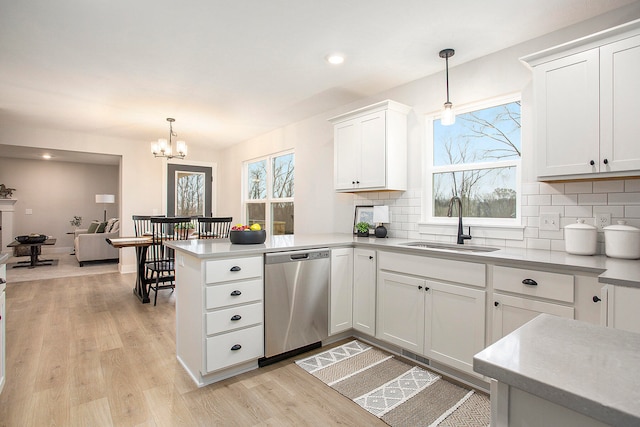 kitchen with stainless steel dishwasher, pendant lighting, white cabinetry, and a wealth of natural light