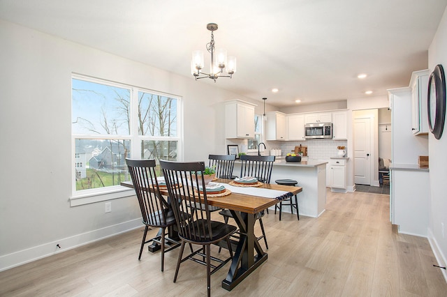 dining space with a wealth of natural light, light hardwood / wood-style flooring, and an inviting chandelier