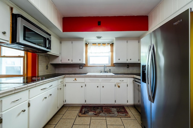 kitchen with tile counters, sink, white cabinets, and appliances with stainless steel finishes