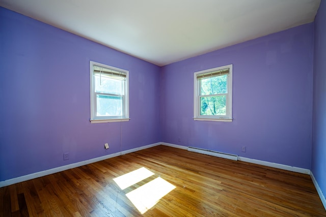 empty room featuring baseboard heating and hardwood / wood-style floors