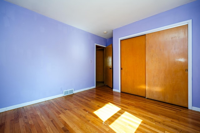 unfurnished bedroom with wood-type flooring and a closet