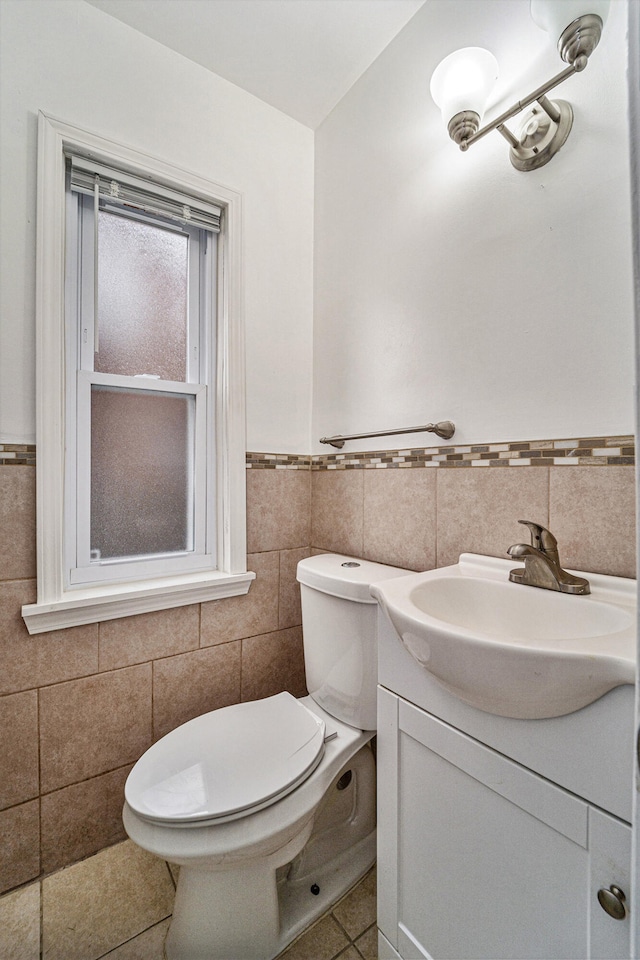 bathroom with tile patterned floors, vanity, tile walls, and toilet