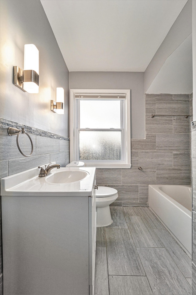 bathroom featuring vanity, tile walls, and toilet