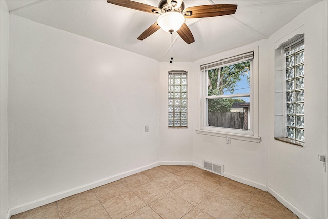 empty room with ceiling fan, plenty of natural light, and lofted ceiling