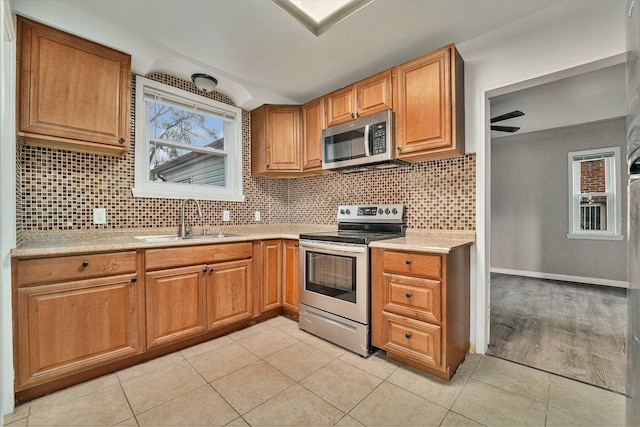 kitchen with backsplash, sink, ceiling fan, light tile patterned flooring, and stainless steel appliances