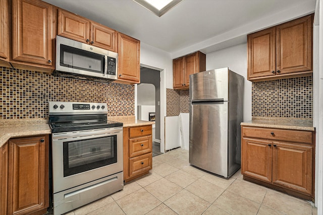 kitchen with backsplash, stainless steel appliances, and light tile patterned flooring