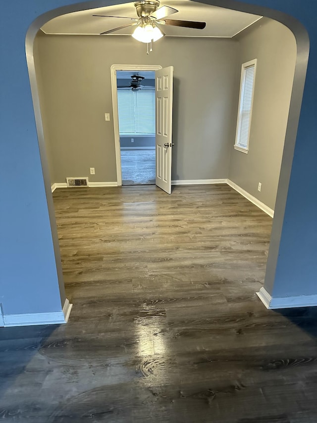 empty room with ceiling fan and dark wood-type flooring