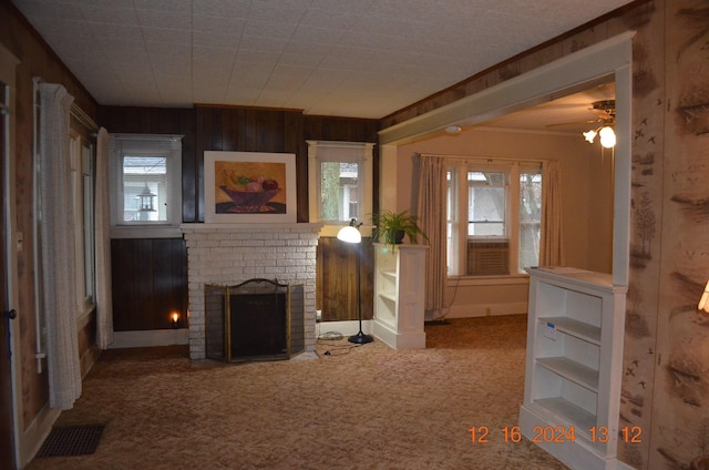 unfurnished living room featuring crown molding, carpet, a fireplace, and wood walls