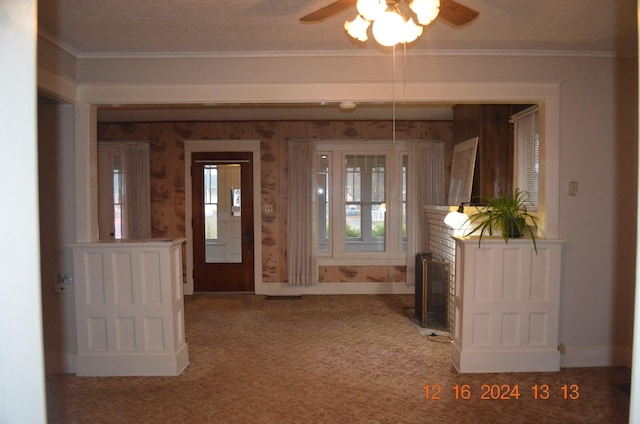 entryway with crown molding, carpet, and a fireplace