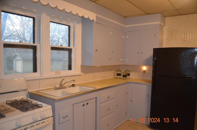 kitchen with sink, white cabinets, white range with gas cooktop, black fridge, and a drop ceiling