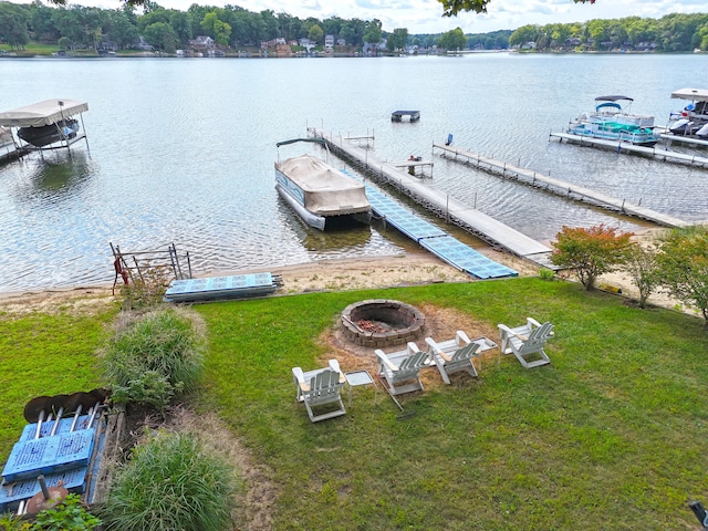 dock area with a fire pit, a water view, and a yard