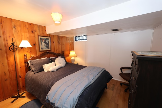 bedroom with wood walls and hardwood / wood-style flooring