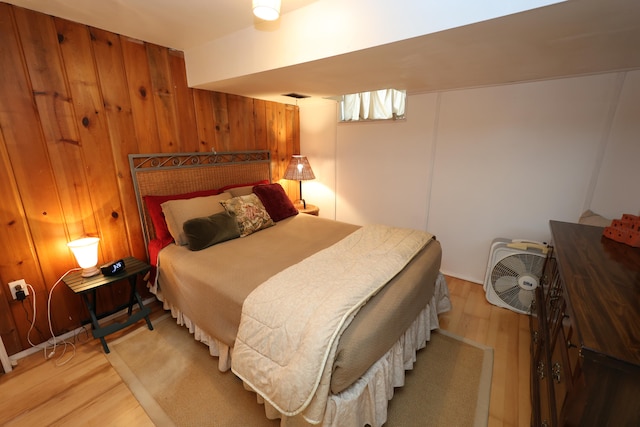 bedroom featuring wooden walls and light hardwood / wood-style floors