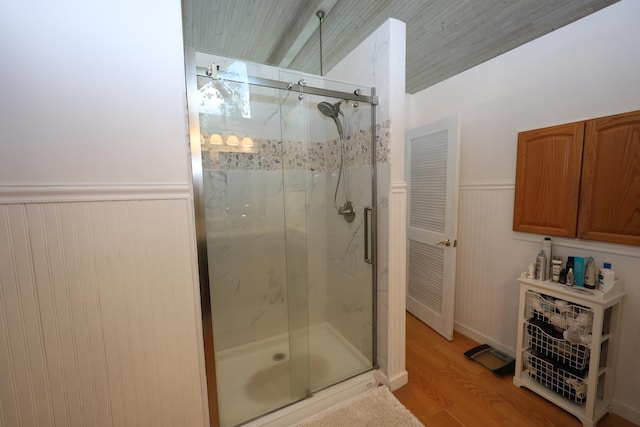 bathroom with an enclosed shower, wooden walls, and hardwood / wood-style flooring